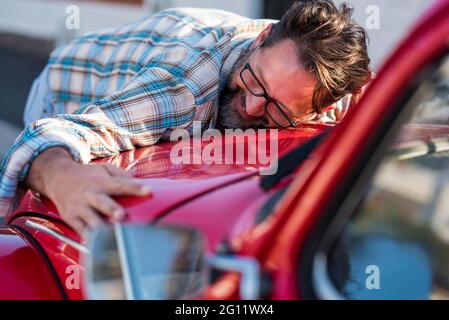 Bell'uomo sopportato è abbracciare la sua nuova auto e sorridente - l'amore per auto veicolo con adulti persone mature in amore e felice - concetto di maschio e auto Foto Stock