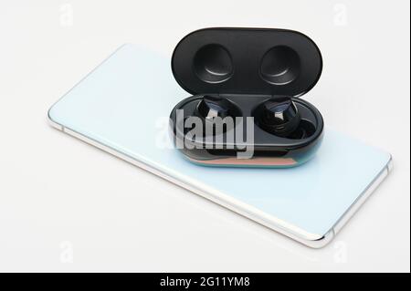Tema ricarica inversa. Caricare gli auricolari wireless dalla batteria dello smartphone Foto Stock