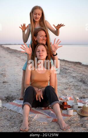 famiglia divertente felice riposarsi sulla riva. mamma e figlie in un pic-nic Foto Stock