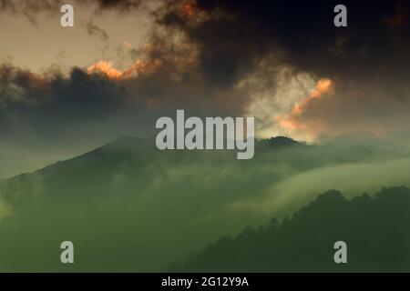 Luce proveniente da una finestra di nuvole dal sole che tramonta, sulle vette del Monte Himalayan. Suggestiva formazione di nuvole con colori del tramonto su mountta indiana Foto Stock