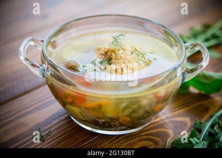 zuppa calda fresca con polpette di pollo e verdure in un piastra su un tavolo di legno Foto Stock