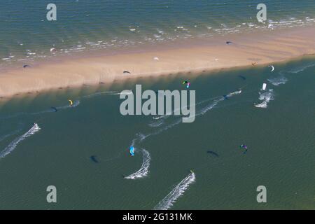 Kitesurfers / kiteboarders tirati da potere aquiloni in giornata ventosa sul Mare del Nord Foto Stock