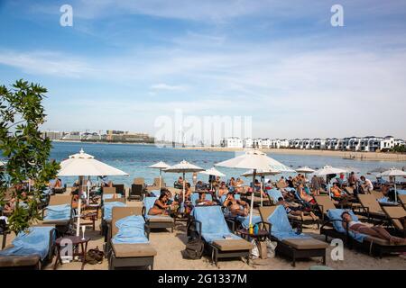 I turisti prendono il sole su Palm Jumeirah con Burj al Arab sullo sfondo. Dubai, 2 dicembre 2018 Foto Stock