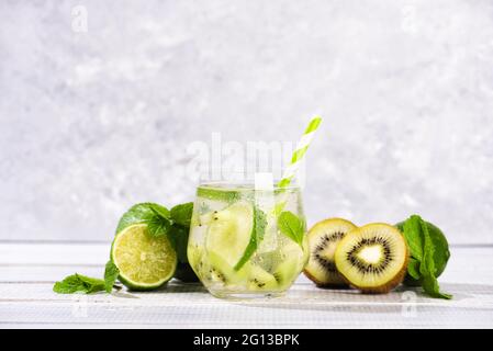 Un bicchiere di mojito cocktail con lime e menta e kiwi su un tavolo di legno grigio. Estati fredde bevande alcoliche Foto Stock