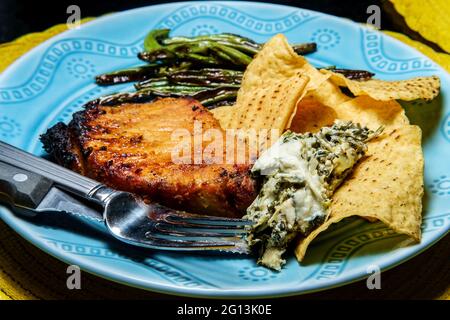 Costolette di maiale marinate alla griglia con fagioli verdi e salsa di spinaci carciofi Foto Stock