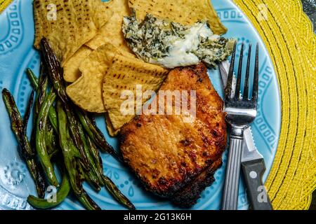 Costolette di maiale marinate alla griglia con fagioli verdi e salsa di spinaci carciofi Foto Stock