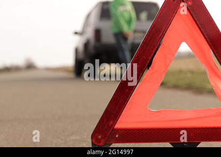 Triangolo rosso di una vettura ferma sulla strada. Un segnale di arresto di emergenza montato sulla strada sullo sfondo della vettura ferma. Il concetto di un organico sicuro Foto Stock