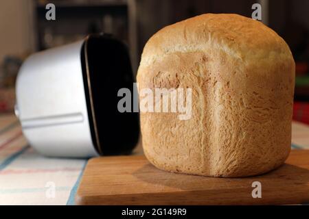 Pane cotto in macchina per il pane su tavola. Messa a fuoco selettiva. Foto Stock