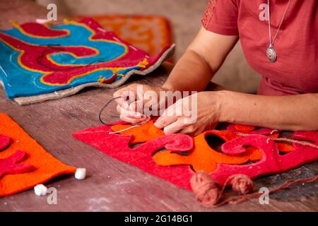 Cucire i pezzi di feltro per fare i contenitori di cuscino di feltro in Issyk Kul, Kirghizistan Foto Stock