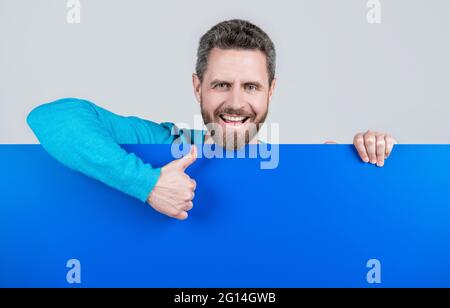 presentazione del prodotto. presentazione delle informazioni di novità. il maschio dietro carta blu mostra il pollice in su. Foto Stock