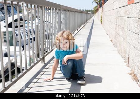 Ragazzo bambino prendere breve pausa hunkering giù sul lungomare, riposo Foto Stock