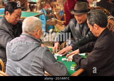 Gli anziani cinesi giocano una partita nazionale mahjong a un tavolo in un parco Foto Stock