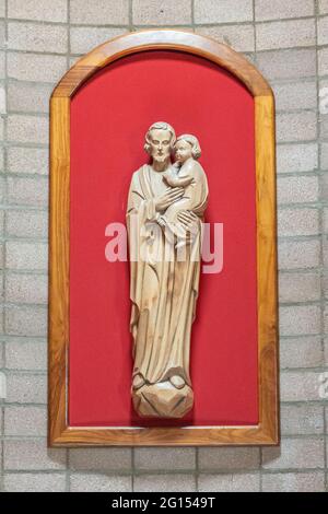 Santa Inez, CA, USA - 26 maggio 2021: Seminario di San Lorenzo, all'interno della chiesa, primo piano di San Giuseppe beige con statua del bambino su sfondo rosso. Foto Stock