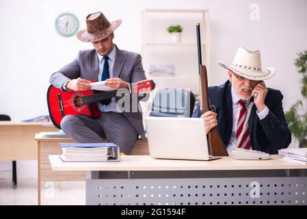 Due impiegati di cowboy maschi durante la pausa in ufficio Foto Stock