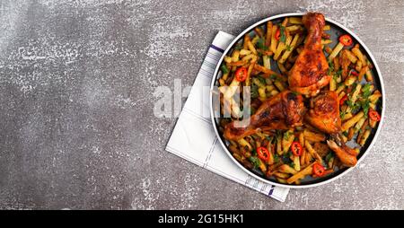 Bastoncini di pollo con patate e peperoni caldi su un piatto rotondo su sfondo scuro. Vista dall'alto, disposizione piatta Foto Stock