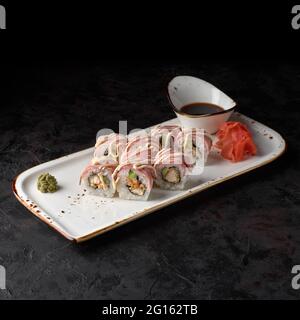 Rotolo Nivatori - con filetto di pollo, cetriolo, pancetta e salsa piccante su fondo nero. Menu sushi. Cibo giapponese. Foto Stock
