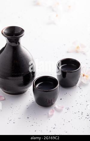 Sake forte in ceramica nera. Abitudine giapponese di bere alcol. Ceramica nera su una pietra bianca. Foto Stock