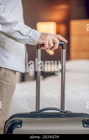 Primo piano immagine di una mano di mans che tiene una valigia Foto Stock