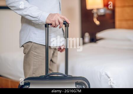 Primo piano immagine di una mano di mans che tiene una valigia Foto Stock