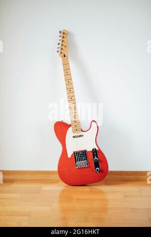 Chitarra elettrica rossa su parete bianca Foto Stock