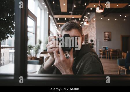 Guy scatta foto nello specchio con una macchina fotografica nelle mani Foto Stock