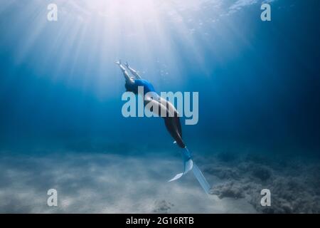 Freewiver femminile con pinne scivolano sott'acqua in oceano con luce solare. Freewiving estivo. Foto Stock