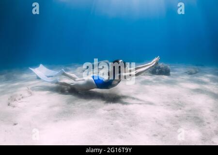 Freewiver femminile con pinne scivolano sott'acqua in oceano con luce solare. Freewiving estivo. Foto Stock