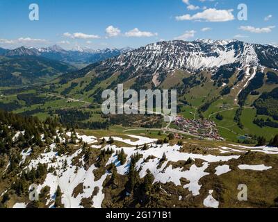 Vista aerea sul villaggio di Oberjoch nelle Alpi dell'Allgau in una giornata di sole a maggio con l'ultima neve nelle montagne più alte Foto Stock
