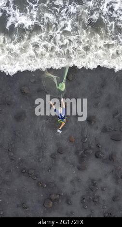 Tamanique, El Salvador. 04 giugno 2021. (NOTA DEI REDATTORI: Immagine presa con un drone) Vista aerea di un pescatore mentre lancia una rete nel mare per catturare il pesce mentre i surfisti catturano le onde di pratica. El Salvador ospita l'ISA World Surfing Games, dove i vincitori riceveranno i biglietti per le Olimpiadi di Tokyo. Credit: SOPA Images Limited/Alamy Live News Foto Stock