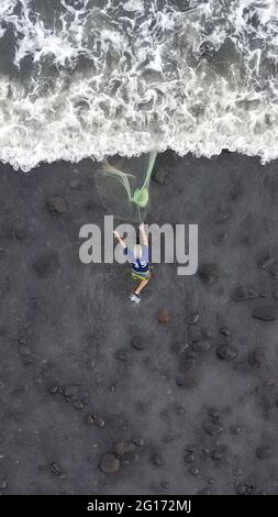 Tamanique, El Salvador. 04 giugno 2021. (NOTA DEI REDATTORI: Immagine presa con un drone) Vista aerea di un pescatore mentre lancia una rete nel mare per catturare il pesce mentre i surfisti catturano le onde di pratica. El Salvador ospita l'ISA World Surfing Games, dove i vincitori riceveranno i biglietti per le Olimpiadi di Tokyo. (Foto di Camilo Freedman/SOPA Images/Sipa USA) Credit: Sipa USA/Alamy Live News Foto Stock