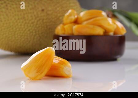 Jackfruit maturo sistemato splendidamente in una ciotola di legno con fondo testurizzato bianco. Foto Stock