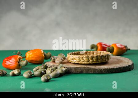 Mela di anacardi e semi di anacardi disposti su una base textured verde con sfondo grigio, fuoco selettivo Foto Stock