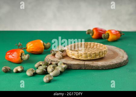 Mela di anacardi e semi di anacardi disposti su una base textured verde con sfondo grigio, fuoco selettivo Foto Stock