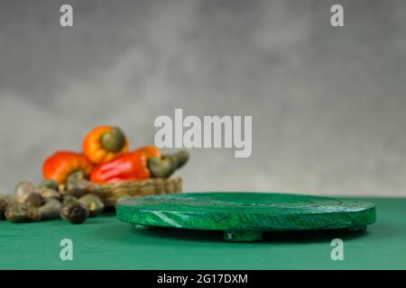 Mela di anacardi e semi di anacardi disposti su una base textured verde con sfondo grigio, fuoco selettivo Foto Stock