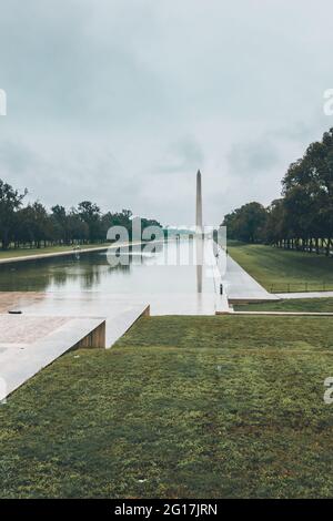 Il Washington Monument a Washinton D.C. alla fine della piscina di riflessione in una giornata piovosa con il Lincoln Memorial sullo sfondo Foto Stock