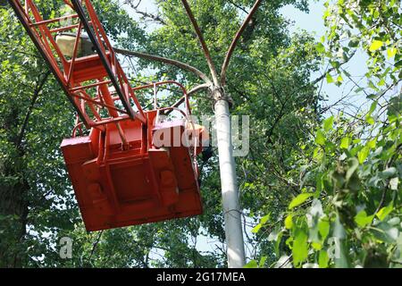 Un lavoratore municipale in apparecchiature di protezione esegue lavori pericolosi per eliminare un'interruzione nella rete elettrica. Un lavoratore ripara una lampada da strada da Foto Stock