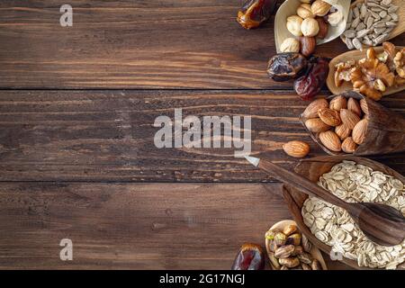 Varietà di grani e noci miste in piastre organiche, su sfondo marrone di legno, vista dall'alto con spazio di copia Foto Stock