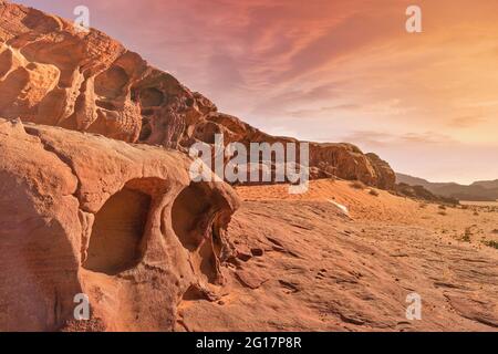 Formazioni rocciose di arenaria rossa illuminate dal sole arancione del pomeriggio nel deserto di Wadi Rum (noto anche come Valle della Luna), Giordania, scena che ricorda Marte pl Foto Stock