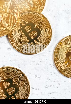 Vista dall'alto, btc commemorativa d'oro - criptovaluta bitcoin - monete sparse su tavola di pietra bianca, dettaglio closeup Foto Stock