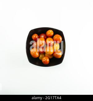 Pomodori freschi messi su un piatto nero su sfondo bianco. Foto Stock