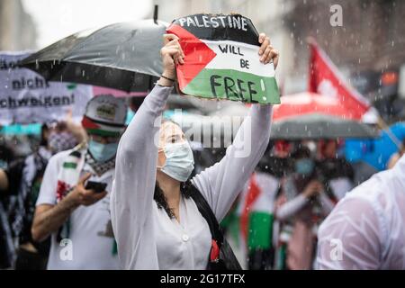 05 giugno 2021, Hessen, Francoforte sul meno: Un partecipante a una manifestazione ha in mano un cartoncino con la bandiera palestinese sul quale è scritto: "La Palestina sarà libera! In una pioggia simile al cloudburst, i partecipanti a una manifestazione pro-Palestina con il motto 'Naksa Day, Long Live the Resistance' si sono recati a Francoforte. La polizia ha garantito la marcia di protesta con un grande contingente. Foto: Boris Roessler/dpa Foto Stock