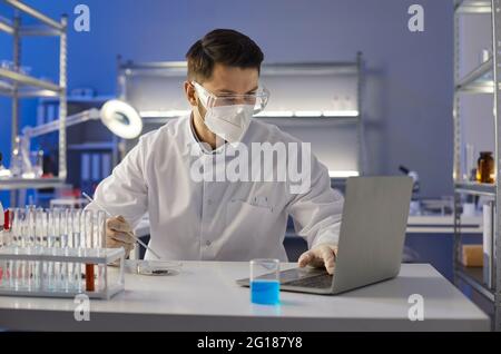 Scienziato che fa ricerche e lavora su un computer portatile in un laboratorio scientifico Foto Stock