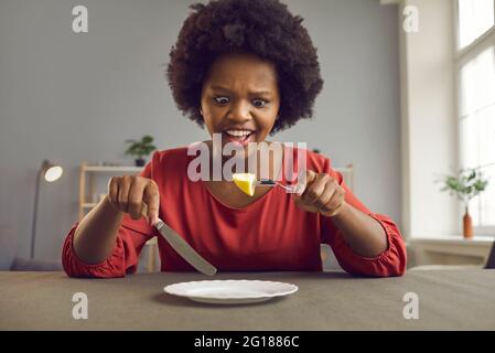 Infelice arrabbiato urlando donna afroamericana sulla dieta guardando un pezzo di mela Foto Stock