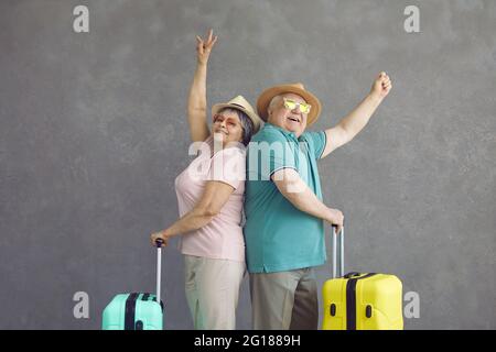 Studio ritratto di felici viaggiatori anziani con le loro valigie in piedi indietro Foto Stock
