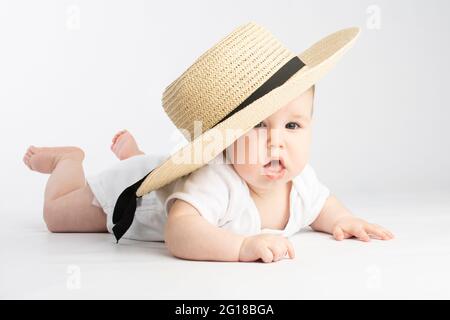 carino bambino in un grande cappello di paglia, su uno sfondo bianco Foto Stock
