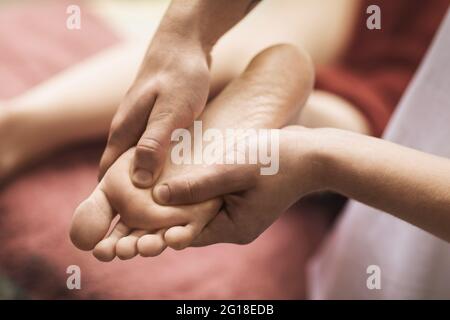 Il massaggiatore esegue un primo piano di massaggio ai piedi. Foto Stock