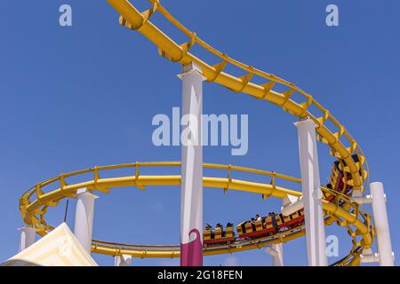 Santa Monica, CA, USA - 20 giugno 2013: Primo piano di una parte delle montagne russe contro il cielo blu. Rotaie gialle e carri rossi. Foto Stock