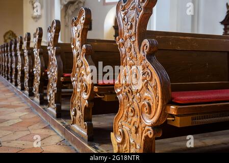 Banchi vuoti all'interno della chiesa in primo piano, banchi in legno intagliato nella cattedrale cattolica, dettaglio dell'interno della chiesa cristiana. Belle vecchie panche, panchine di culto Foto Stock