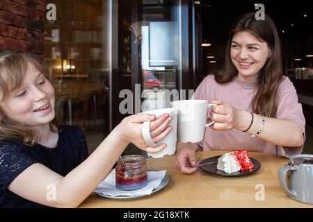 Due ragazze in un caffè bere tè e viziarsi con i dessert. Foto Stock