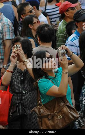 Due donne asiatiche catturano immagini digitali dei luoghi d'interesse nell'affollata Piazza della Signoria, il cuore storico di Firenze, capitale regionale della Toscana, Italia, a metà luglio, vicino al culmine dell'alta stagione estiva. Tra le attrazioni della ‘Dtroviamo il Palazzo Vecchio, la statua del Cavido di Michelangelo, la Fontana di Nettuno o la Fontana del Nettuno e la Loggia dei Lanzi, risalente al XIV secolo, unica galleria di sculture in rilievo da cui è stata scattata questa fotografia. Foto Stock